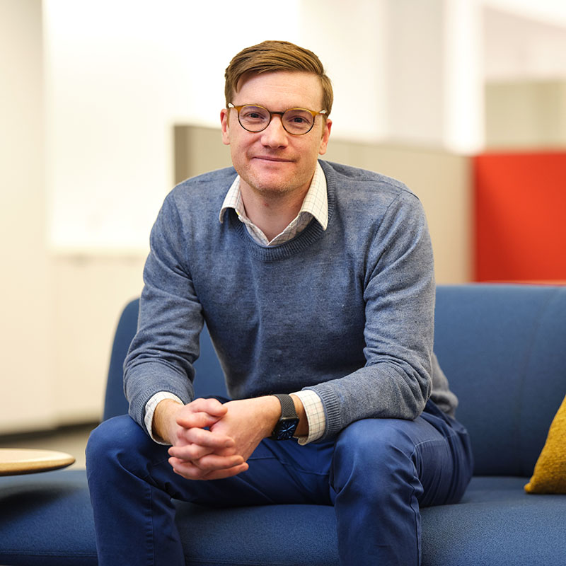 Smiling man with glasses leaning against doorway of conference room at Alkermes