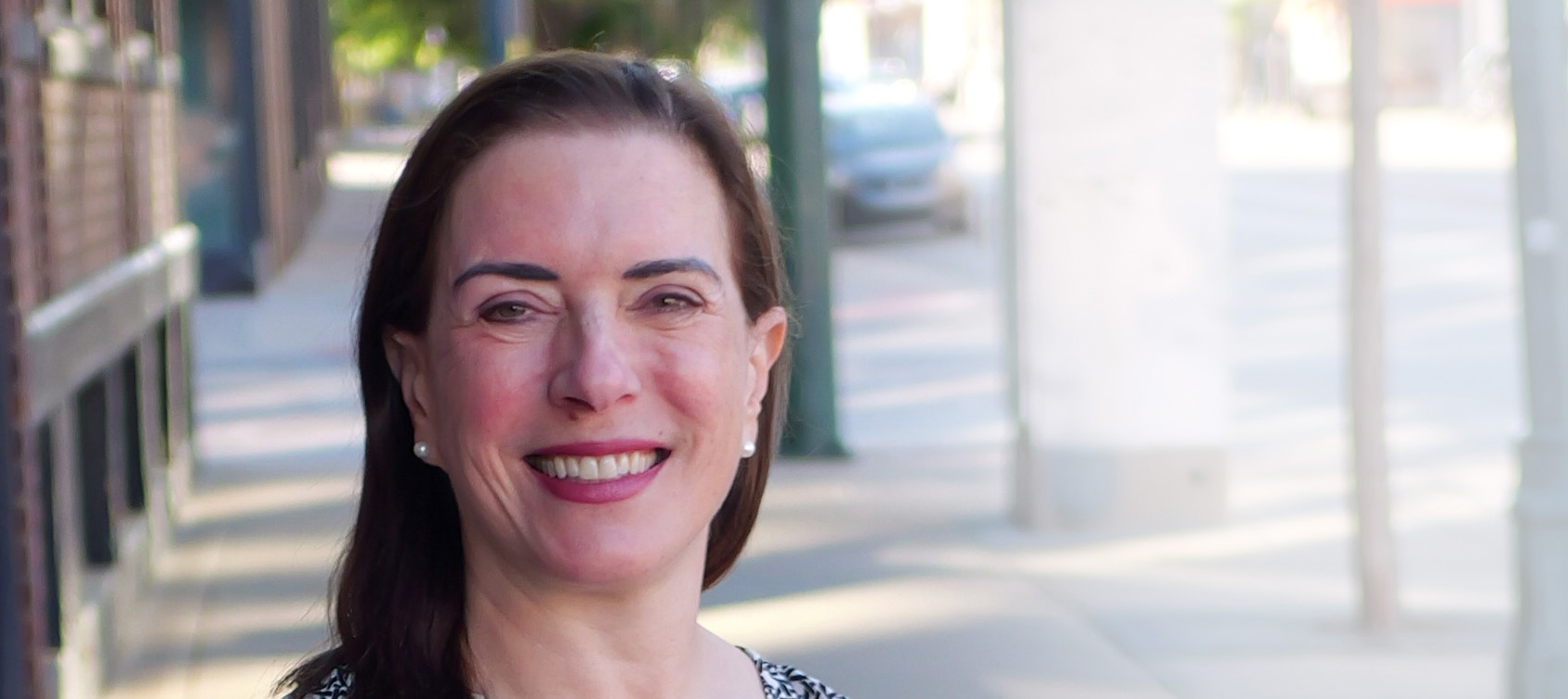 smiling woman standing on sidewalk
