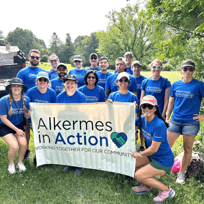 Group of Alkermes team members standing together holding a banner